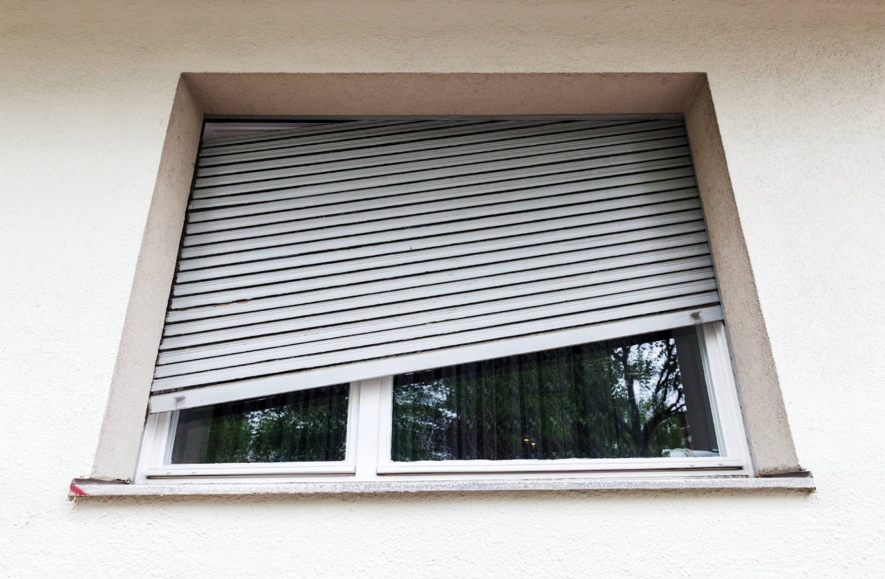 Broken blinds a quarter-drawn but slanting in a window near North Dartmouth, MA